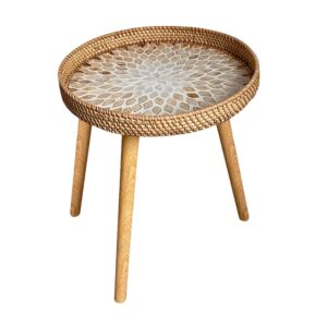 A round side table with three tapered light wood legs. The tabletop features a sunburst shell mosaic pattern in white and tan, surrounded by a raised edge made of woven natural rattan.