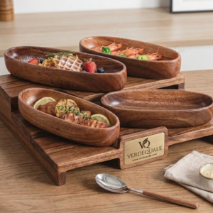 A multi-tiered wooden serving stand holding four empty, boat-shaped wooden bowls. The stand features a brass-toned plaque with the Verdequale VQ logo. The tableware is set on a wooden table alongside gold appetizer forks and an embroidered linen napkin.